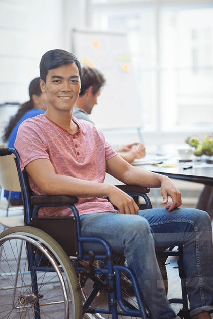 Young man in wheelchair smiling in office setting